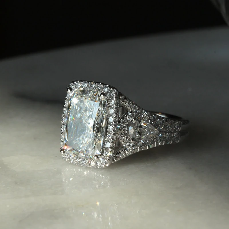 Radiant cut diamond engagement ring with halo, side diamonds, and split shank band