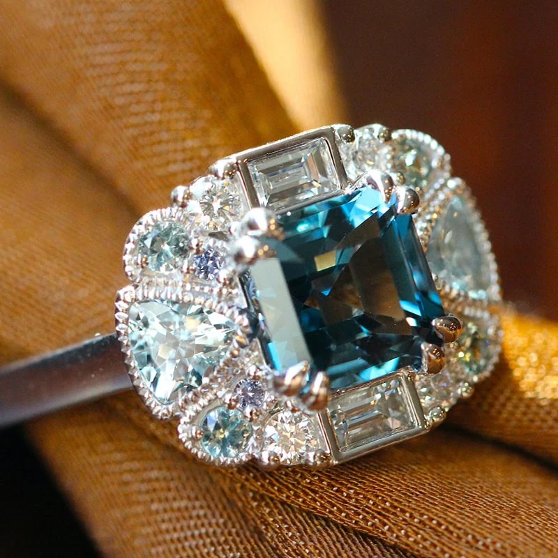 Blue gemstone ring with diamond halo and mixed diamond side stones