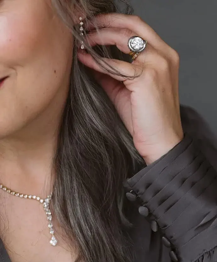 Woman wearing a diamond halo ring and delicate diamond necklace