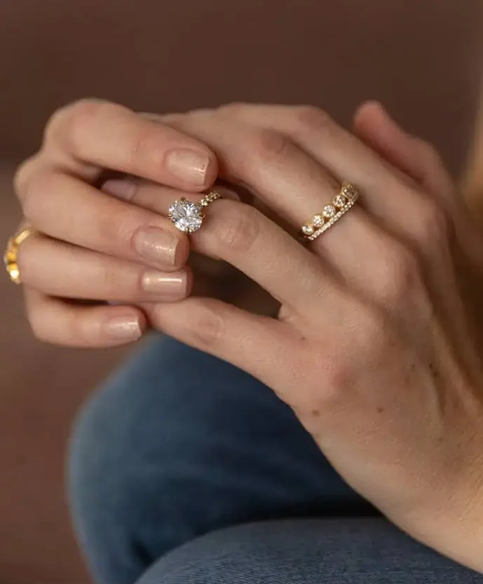 Woman wearing a round diamond engagement ring with a diamond wedding band