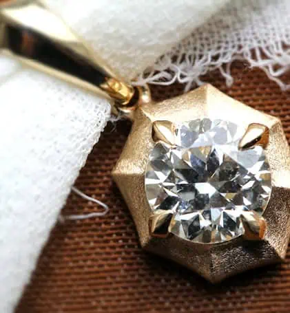 Gold pendant necklace with round diamond in geometric setting