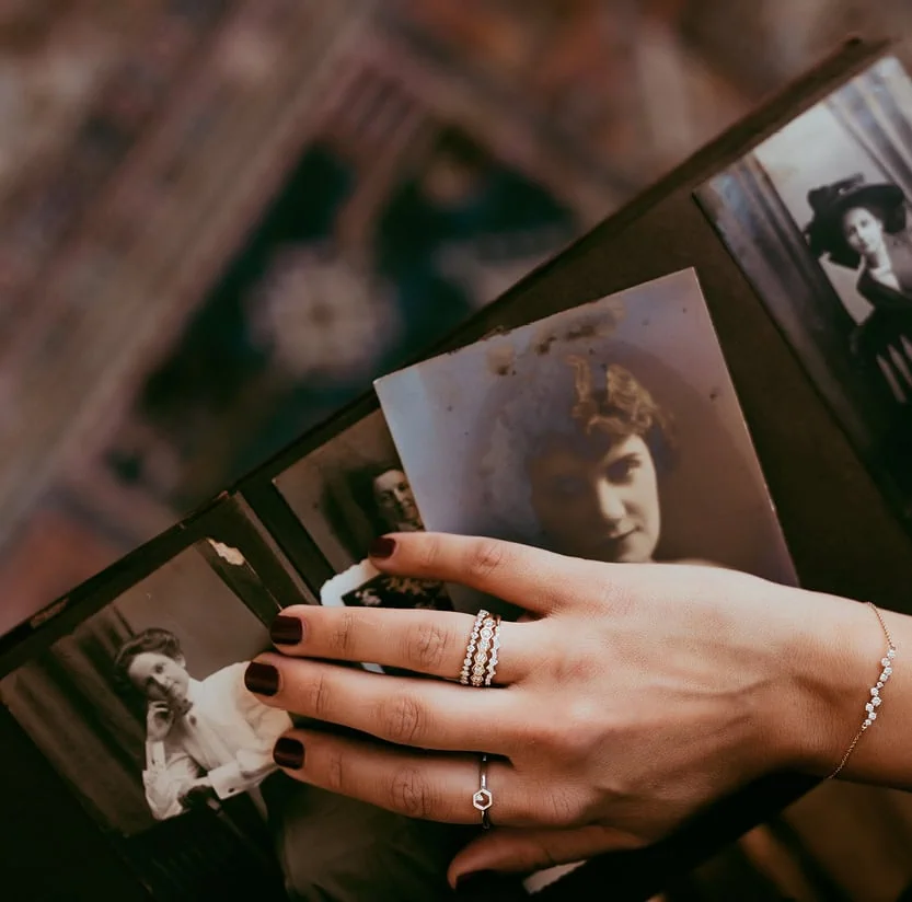 Hand wearing diamond rings resting on vintage photographs