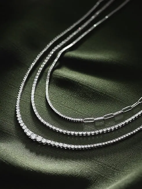 Layered diamond necklaces displayed on green fabric