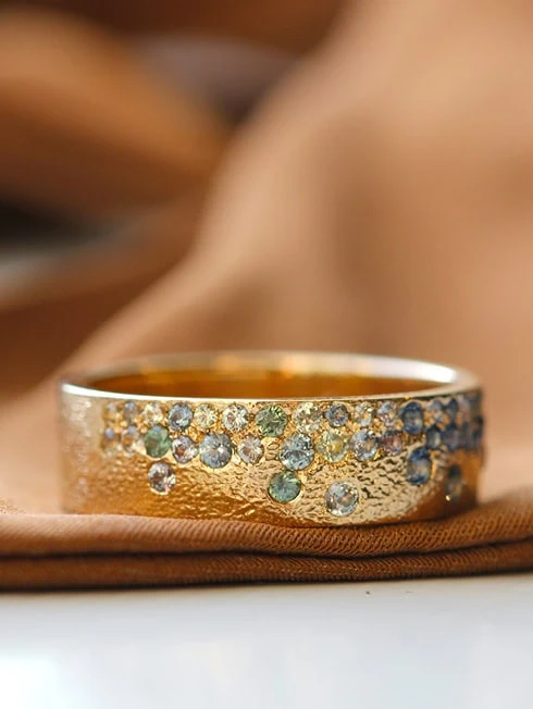 Gold band with small blue and white gemstones set along the surface