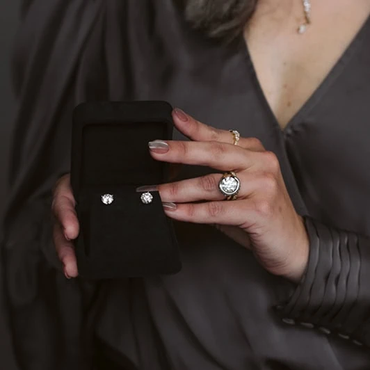 Hands holding a display of diamond stud earrings