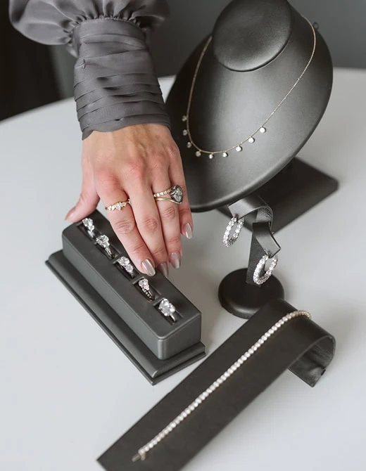 Hand selecting a ring from a jewelry display with necklaces and earrings