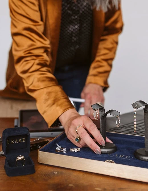 Jewelry designer arranging earrings and rings on a jewelry display tray