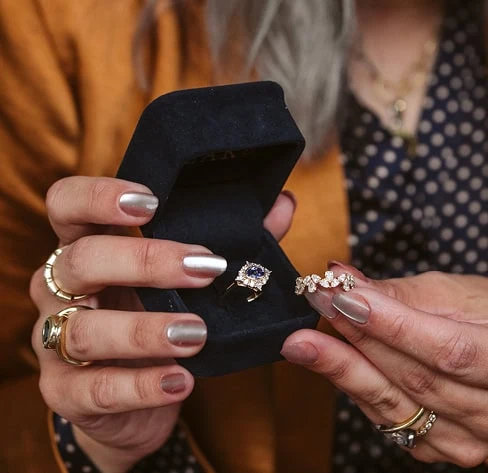 Jeweler holding a diamond ring and band while evaluating jewelry for repair