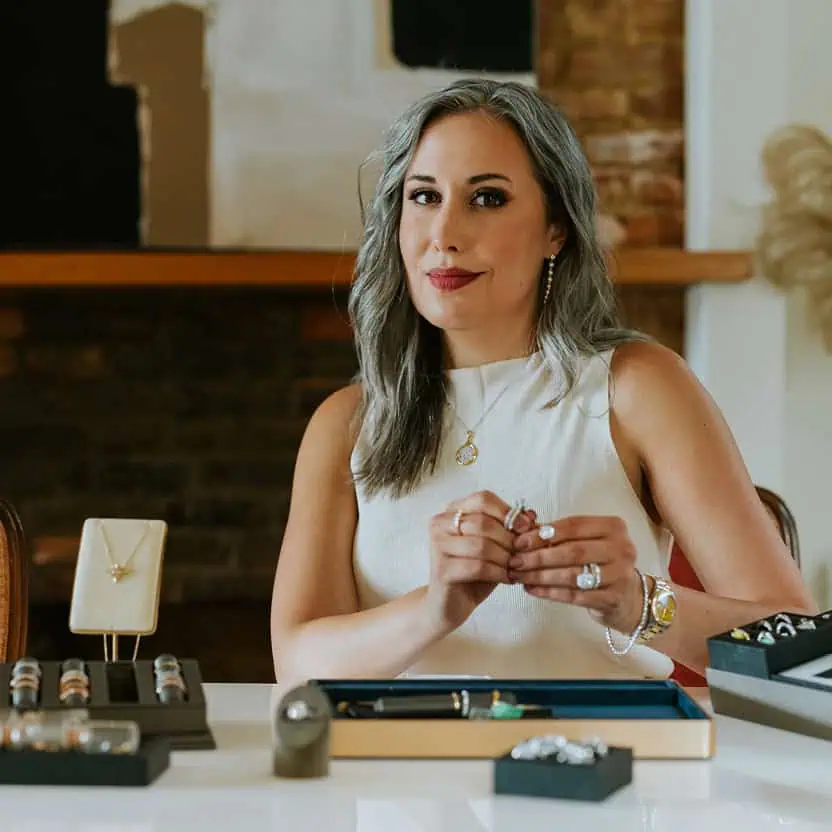 Jewelry designer at The Leake Co. reviewing diamonds and custom jewelry pieces at her workbench in Louisville, Kentucky